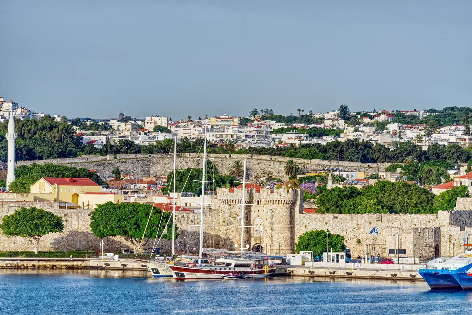 Yachthafen von Rhodos mit steinerner mittelalterlicher Stadtmauer und Booten im Hafen